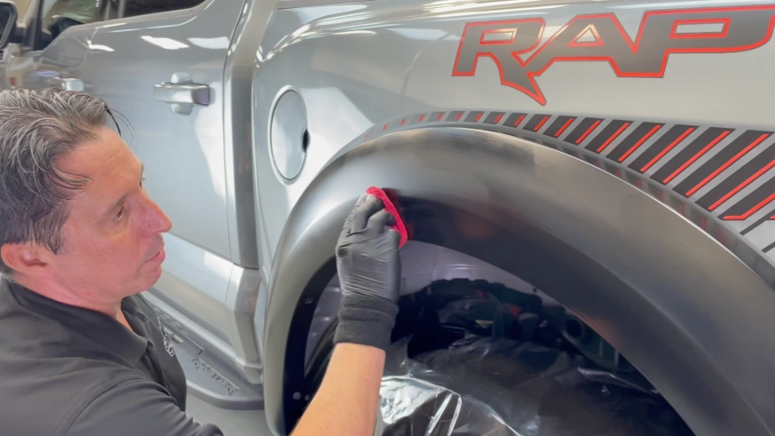 Bill applying ceramic coating to restore and protect the black plastic trim and fender flares on a 2024 Ford F-150 Raptor.