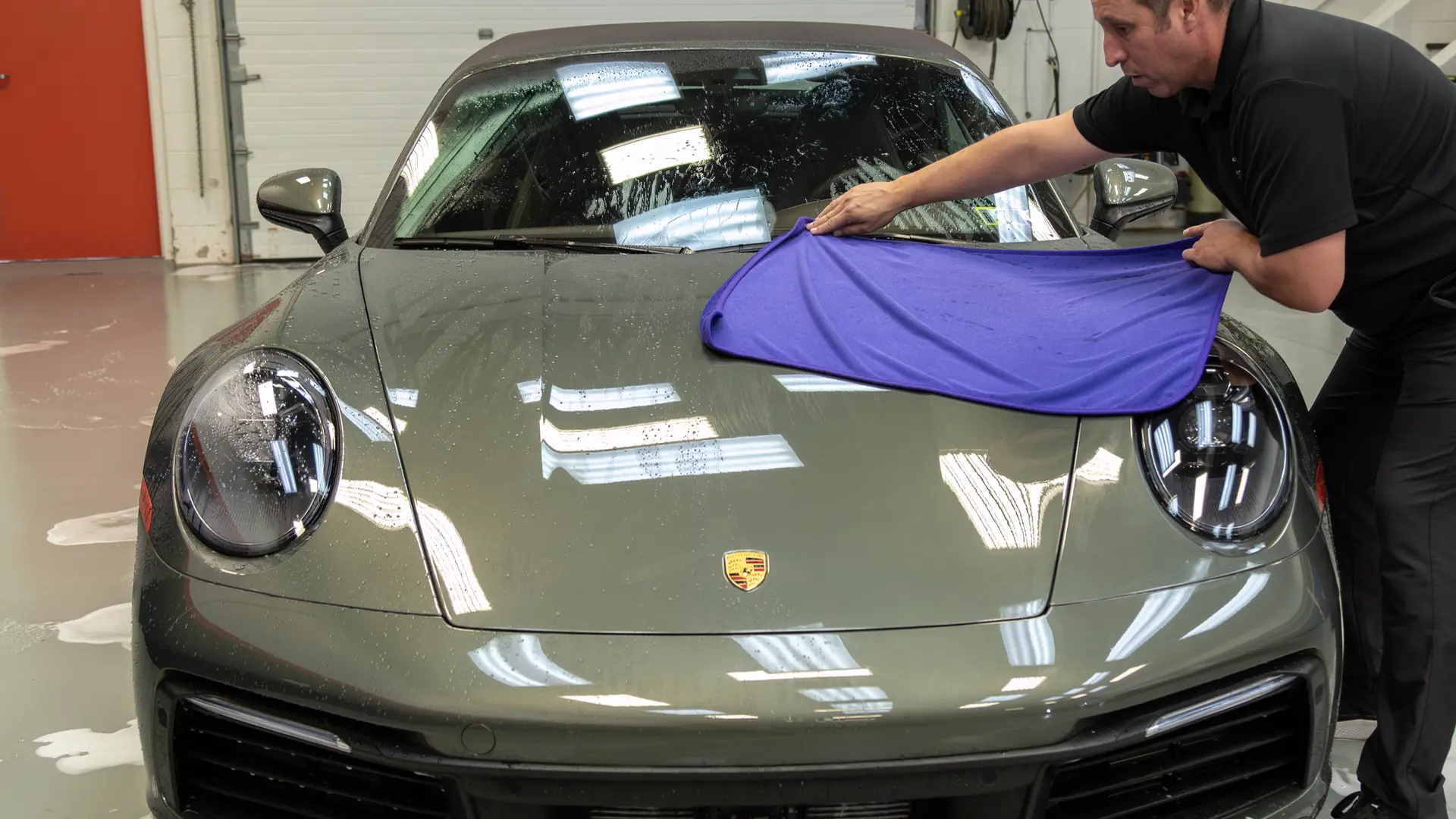 For the final step in the best way to hand wash car exteriors safely, Immaculate Paint Protection founder Bill Fetter uses a premium Gyeon Silk Dryer car wash towel to gently pull water off the hood of a 2020 Porsche 911 Convertible. Because this vehicle is protected with a slick Gyeon ceramic coating, the water easily glides off into the towel, making the drying process incredibly fast and completely scratch-free.