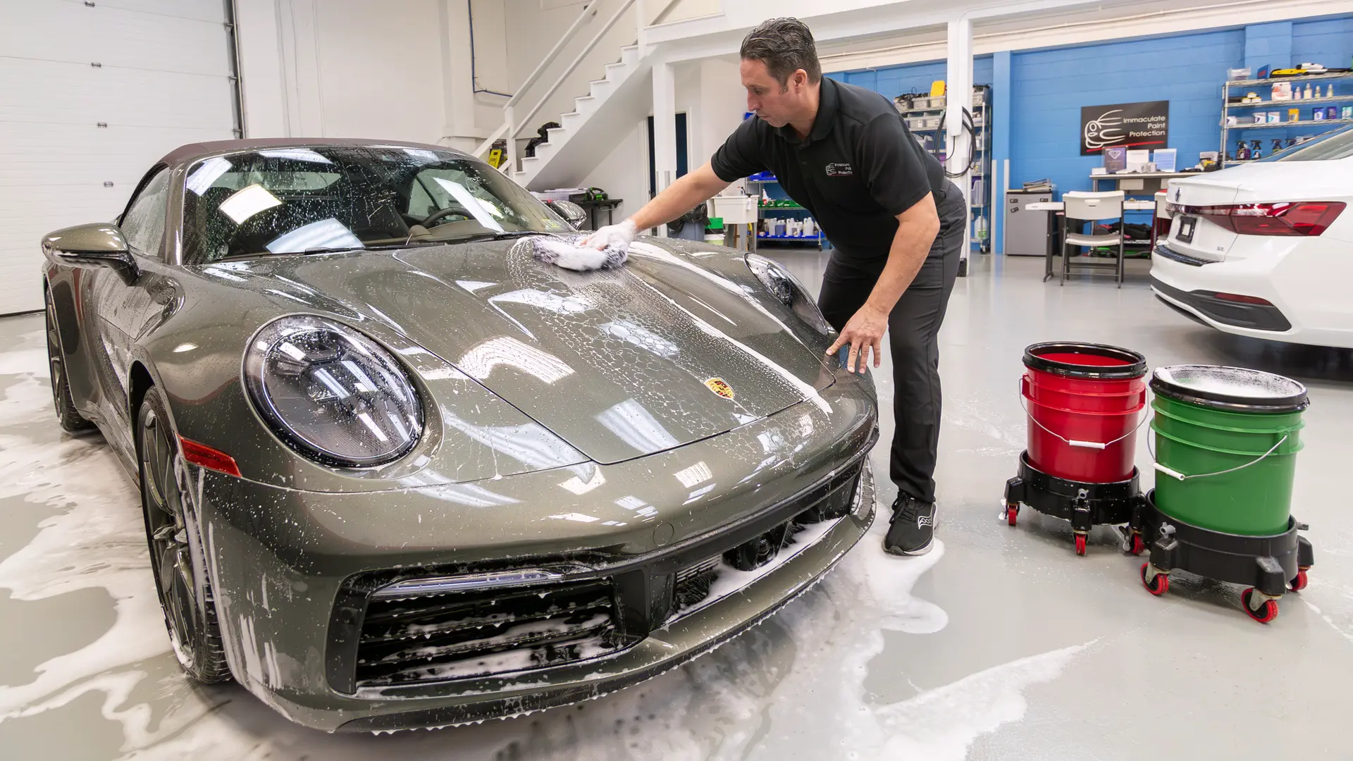 A crucial technique for anyone learning how to wash a car properly by hand is the two-bucket method. Here, Immaculate Paint Protection founder Bill Fetter demonstrates the best way to hand wash car exteriors safely on the hood of a 2020 Porsche 911 Convertible. Using a premium microfiber wash mitt, Bill pulls fresh suds from a green bucket filled with Gyeon Bathe soap and rinses dirt off in a red bucket of clean water to ensure a scratch-free contact wash.