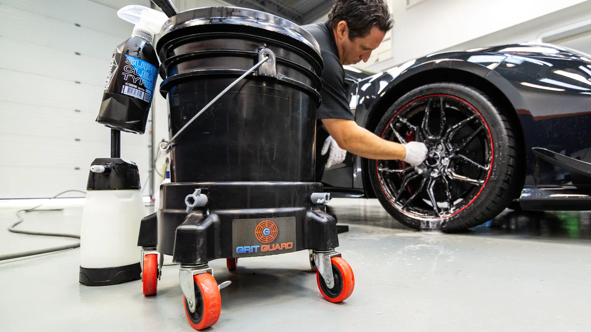 When washing a car by hand, a common mistake is not cleaning the wheels and tires first. The best way to hand wash car exteriors safely is to use a dedicated wheel bucket. Shown here on a Grit Guard dolly next to a 2023 Chevrolet Corvette Z06 in Carbon Flash Metallic, this dedicated setup ensures harsh wheel contamination never transfers back onto the paint.
