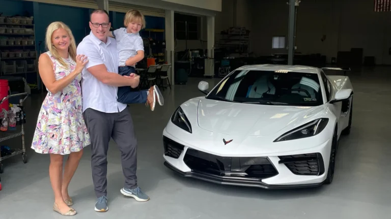 A happy local family consisting of a mom, dad, and young son smiling next to their newly protected white 2023 Chevrolet Corvette at the Immaculate Paint Protection shop in the Lehigh Valley.
