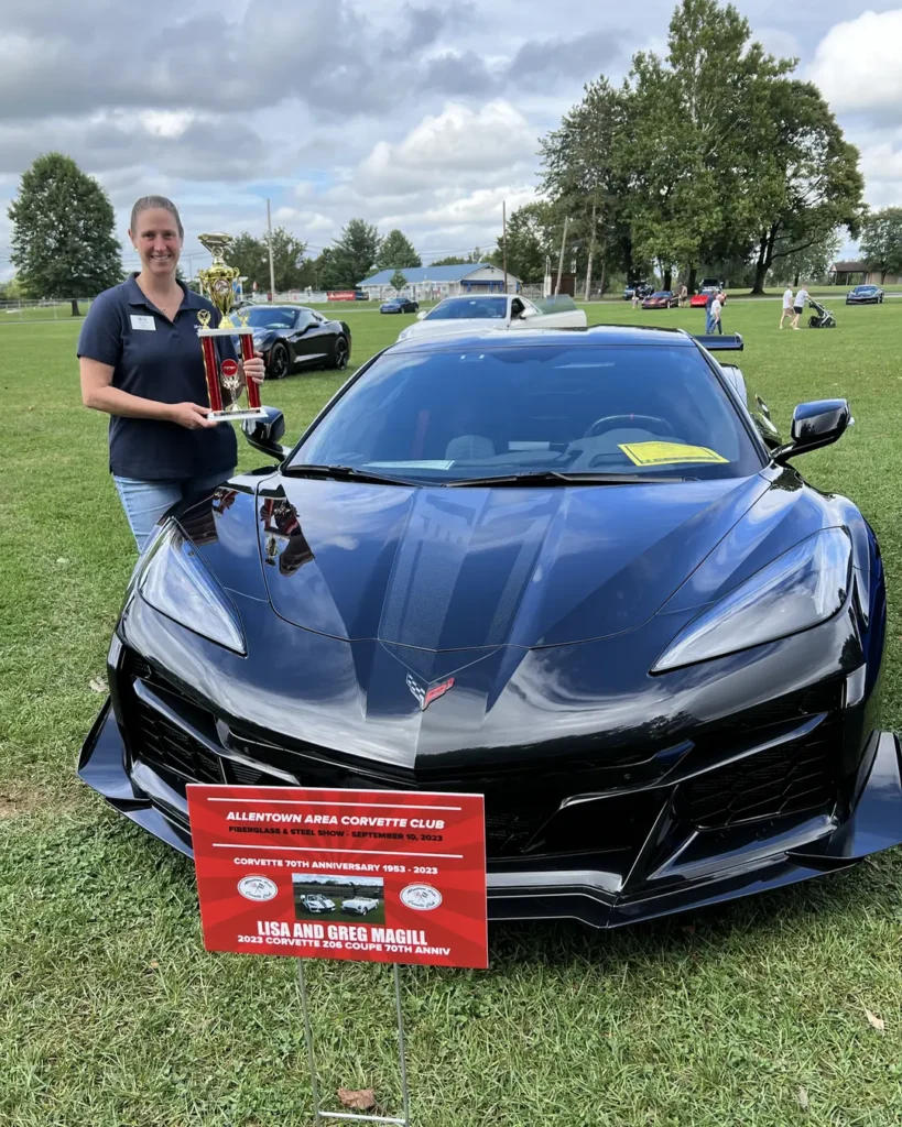 Lisa holds an award while standing next to her black 2023 Corvette Z06 that is protected with Paint Protection Film.