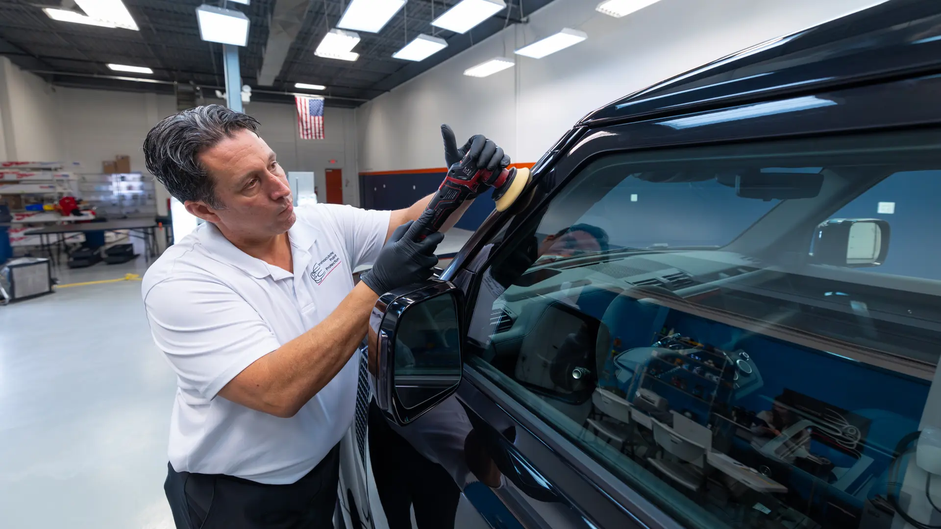 Bill Fetter using a compact Flex PXE 80 cordless polisher with a 3-inch pad to perform precision paint correction on the A-pillar of a Santorini Black Land Rover Defender.