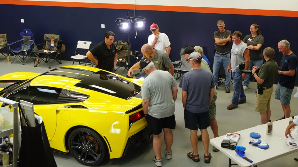Allentown Area Corvette Club members inspect a yellow Corvette that was just machine polished by Bill of Immaculate Paint Protection.